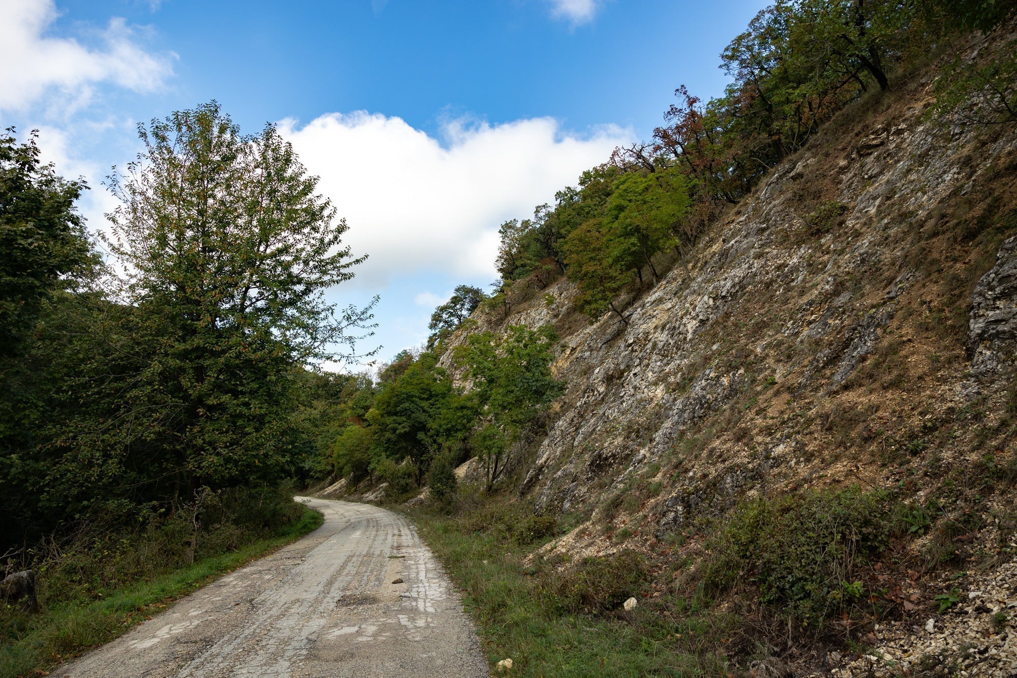 Gravel road next to a rocky mountain hill